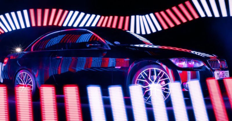 A black car surrounded by red and white neon lights.