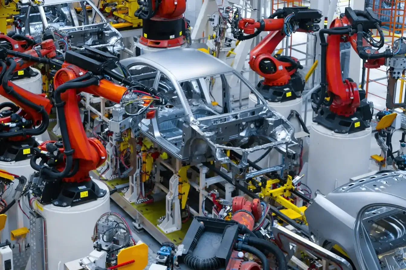 Car assembly line with multiple robotic arms and track.