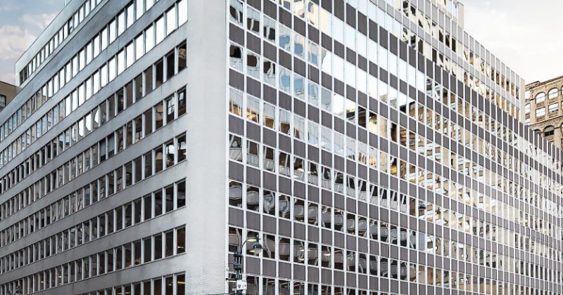 The corner of a building with reflective glass windows.