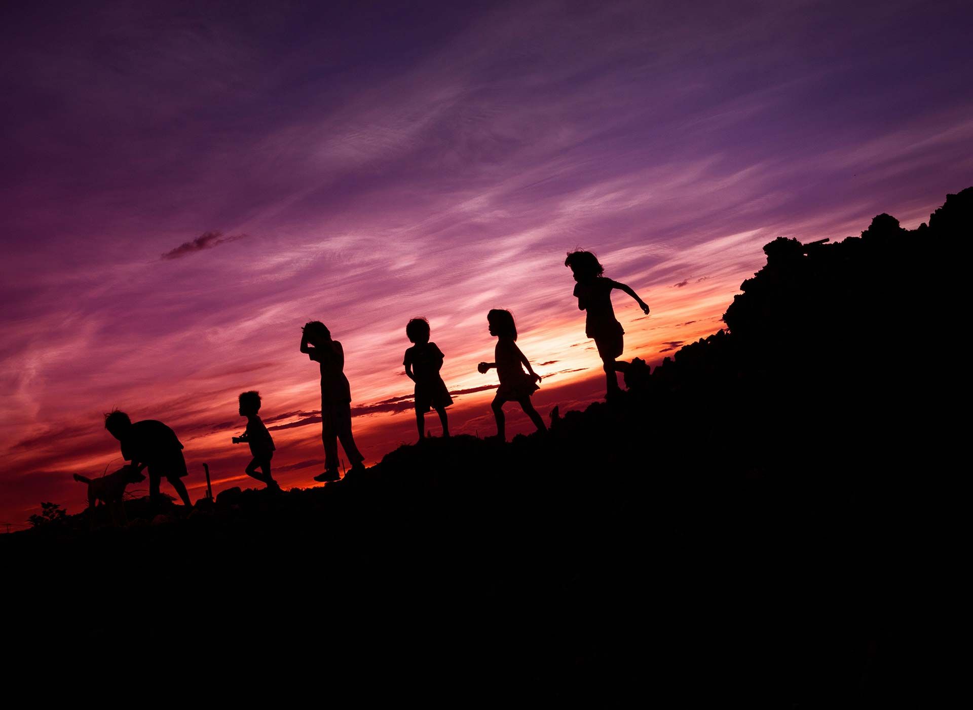 Sunset image of a group of children on a slope in silhouette