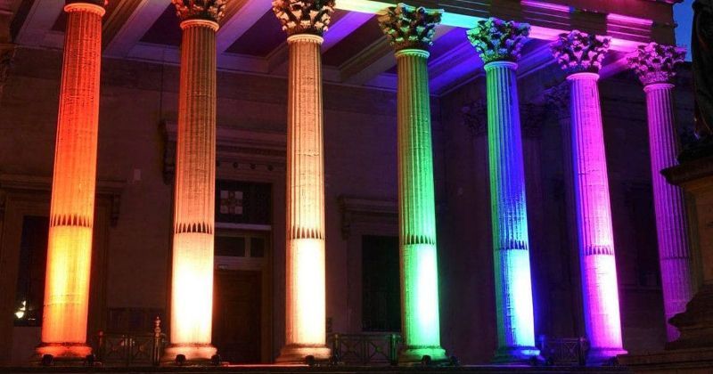 Pillars of a building lit up by technicolour lights.