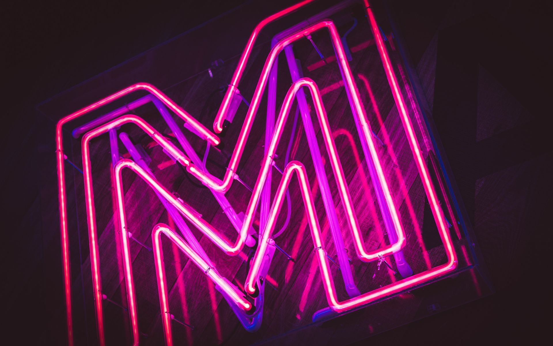 A series of neon M's in purple, one inside the other - black background