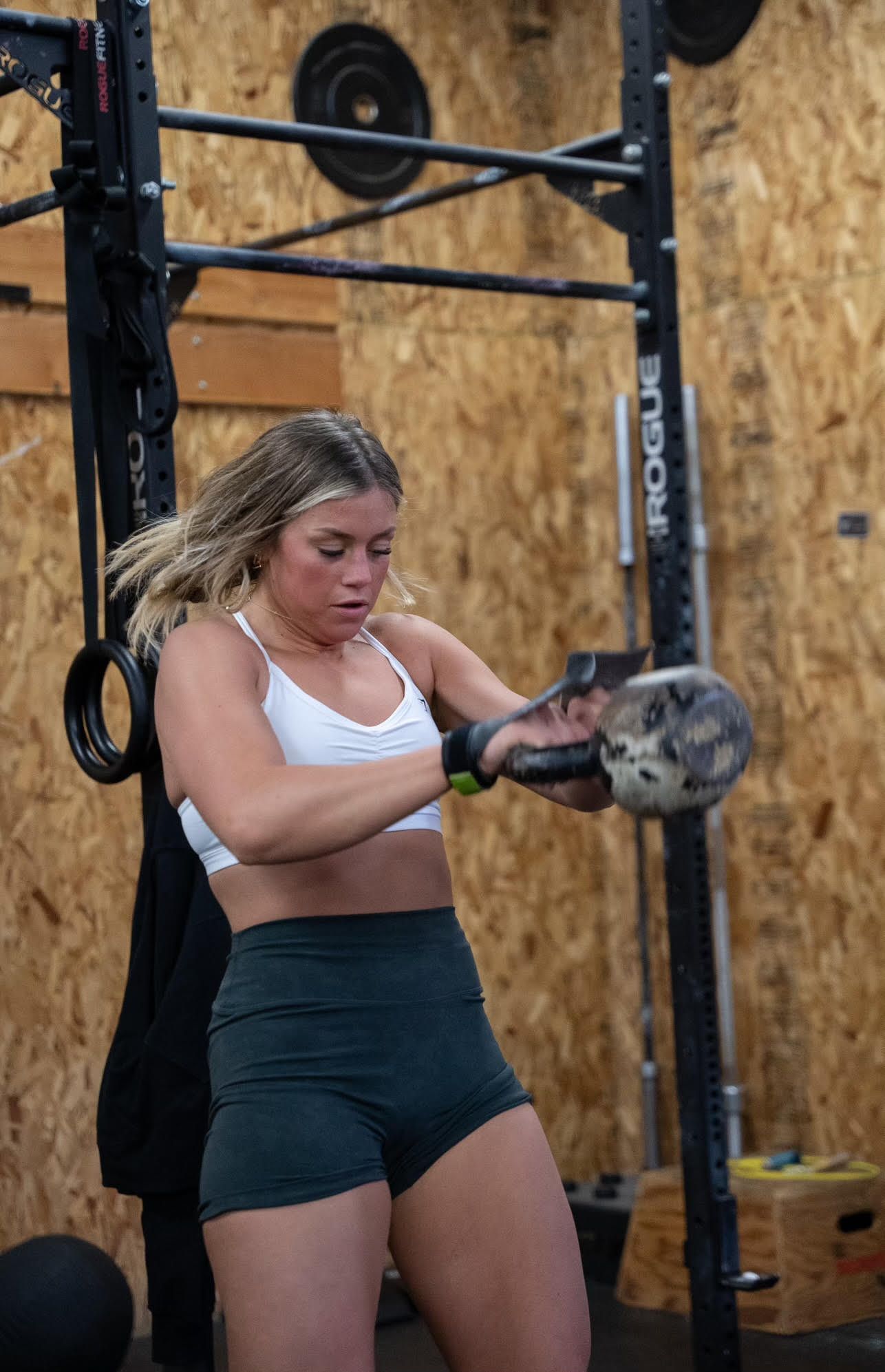 A woman is lifting a kettlebell in a gym.