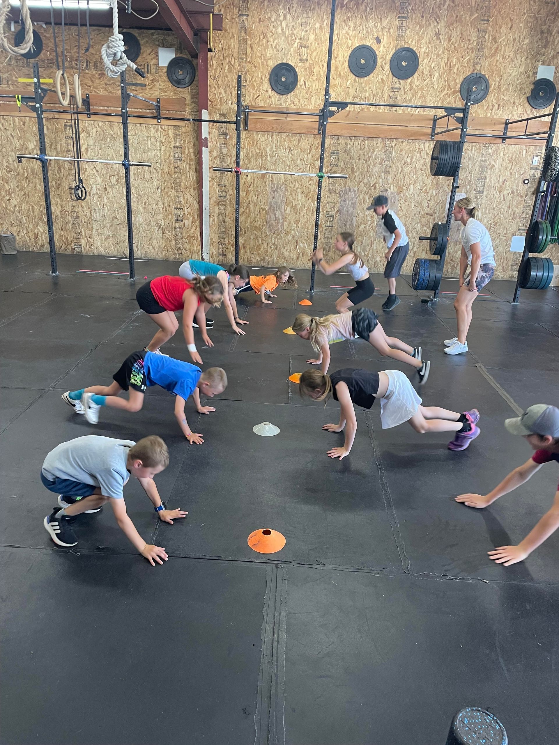 A group of children are doing push ups in a gym.