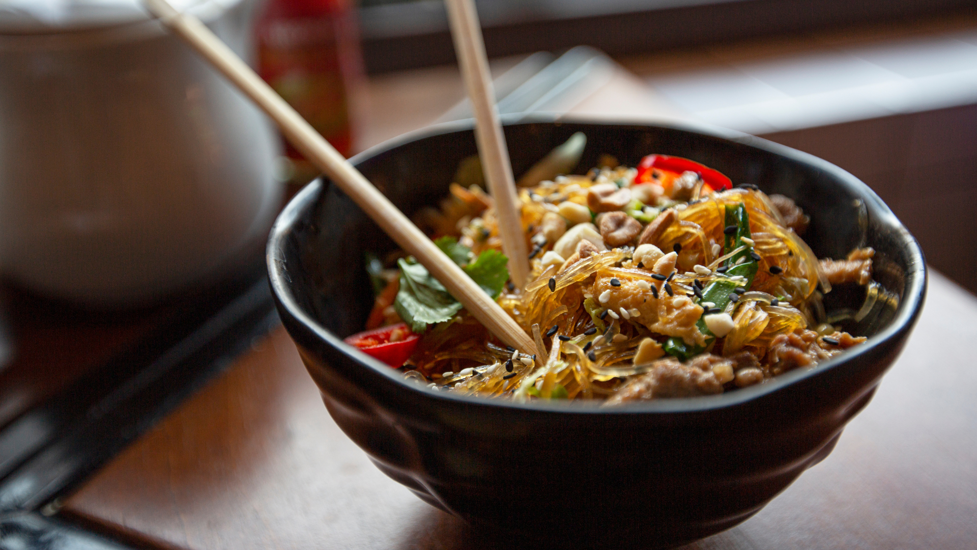 A bowl of food with chopsticks in it on a table.