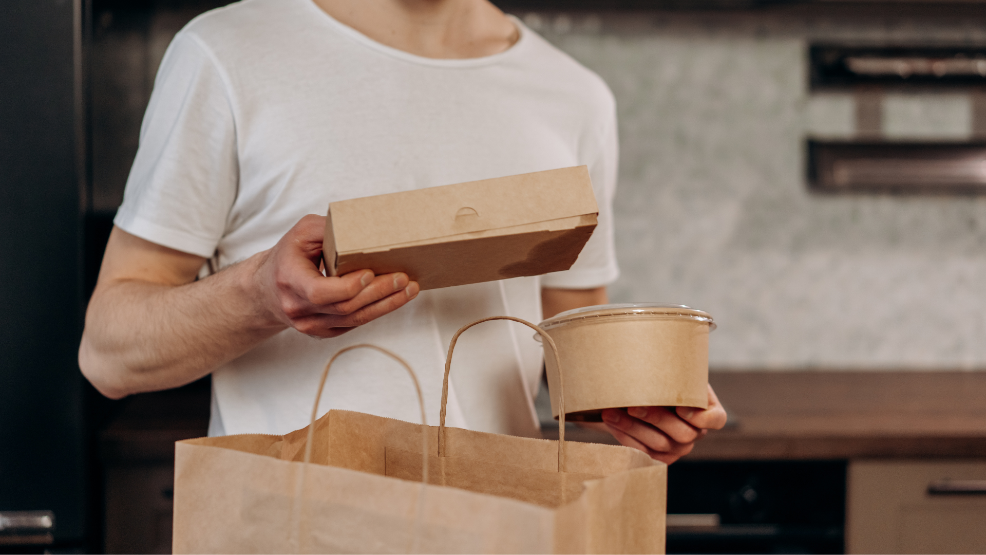 A man is holding a paper bag and a cardboard box.