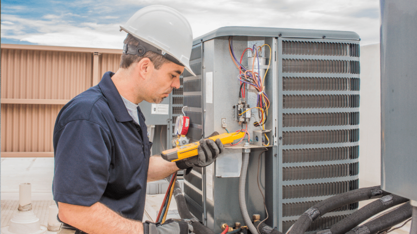 Technician using a multimeter to inspect HVAC equipment outdoors