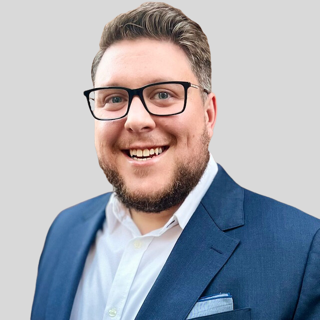 A man in a blue suit and white shirt is smiling