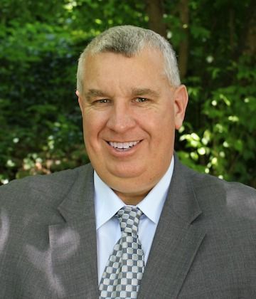 A man in a suit and tie is smiling for the camera.