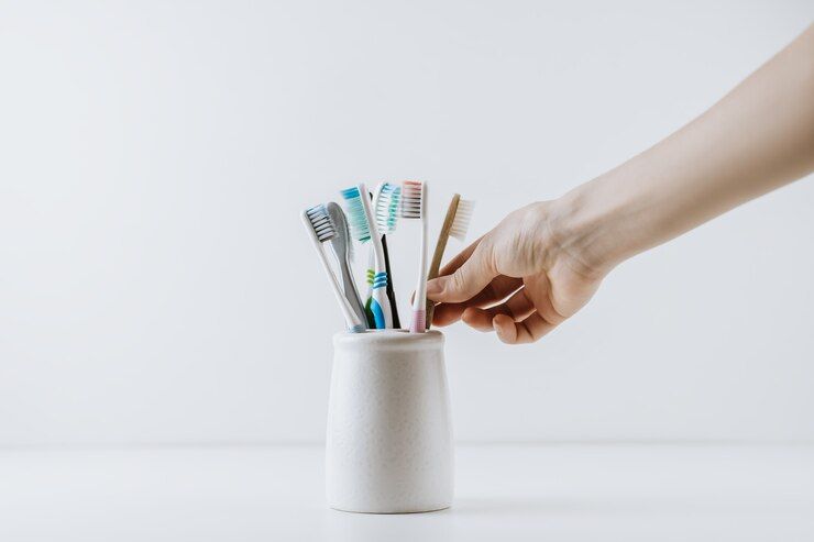 A person is choosing a toothbrush out of a cup of toothbrushes.