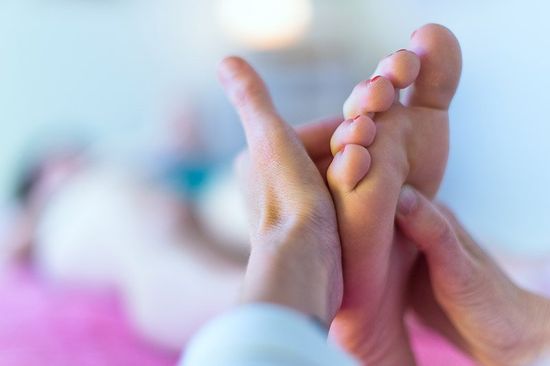 Mani massaggiano il piede di una paziente