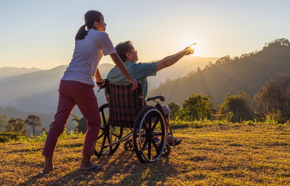 A Man in a Wheelchair Gestures Towards a Woman on a Hill, Capturing a Scene of Interaction and Engagement — Psychology Practice In Tweed Heads, NSW