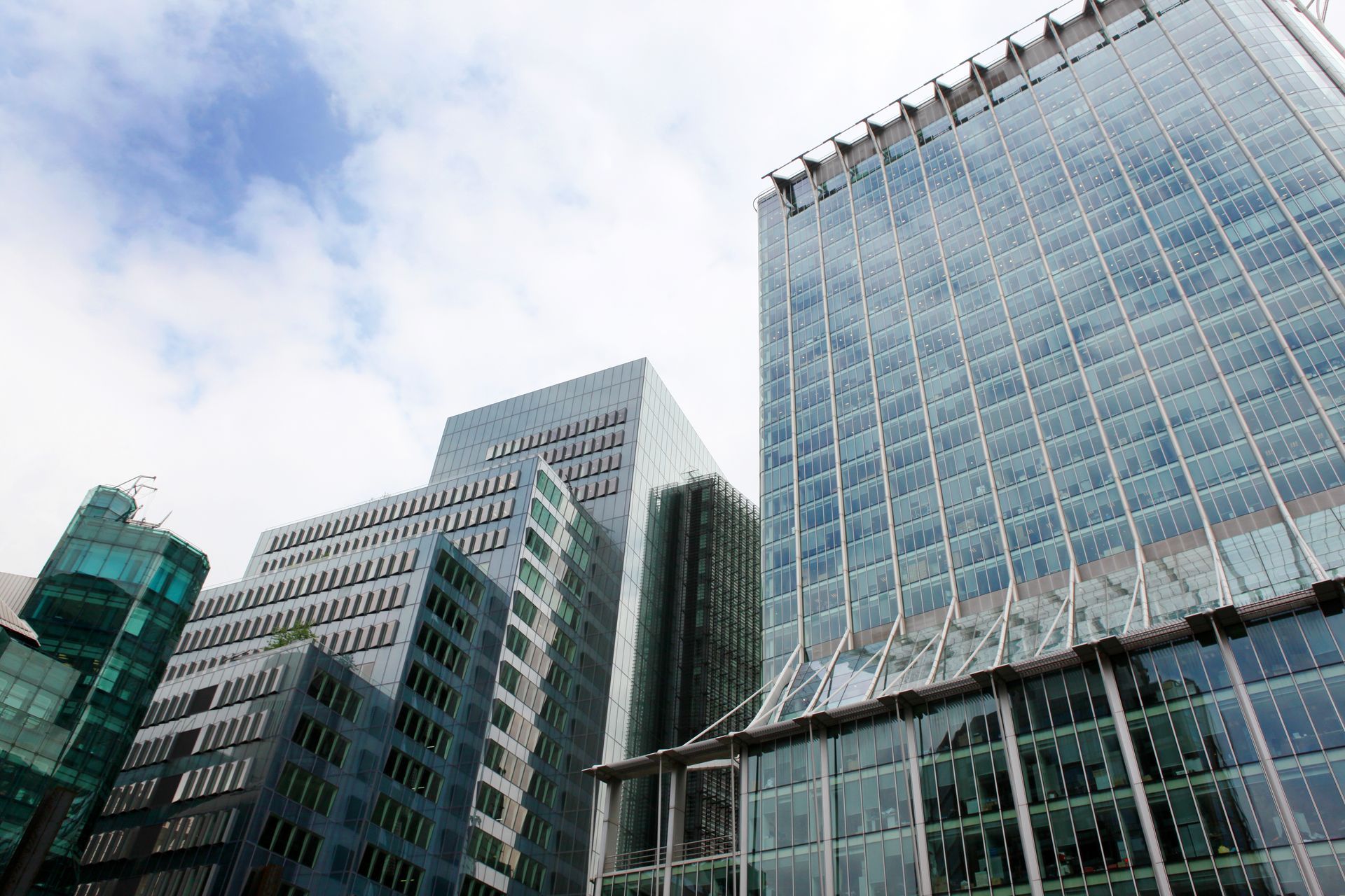 Skyscrapers with glass and metal exteriors against a partly cloudy sky.