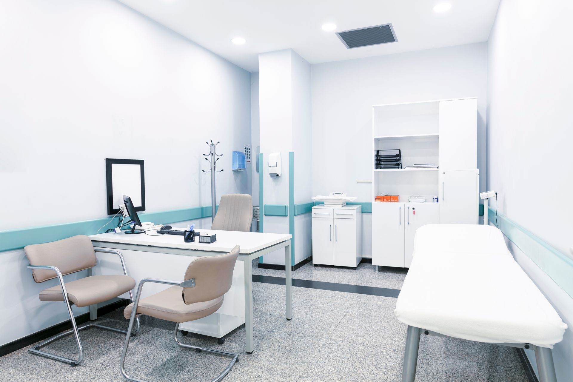 Doctor's office with desk, chairs, medical bed, and storage cabinets, painted white and light blue.