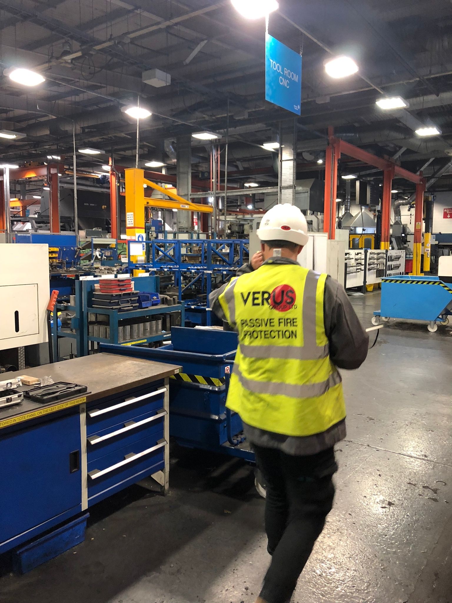 Two men in orange safety vests examine a tablet in front of large solar panels
