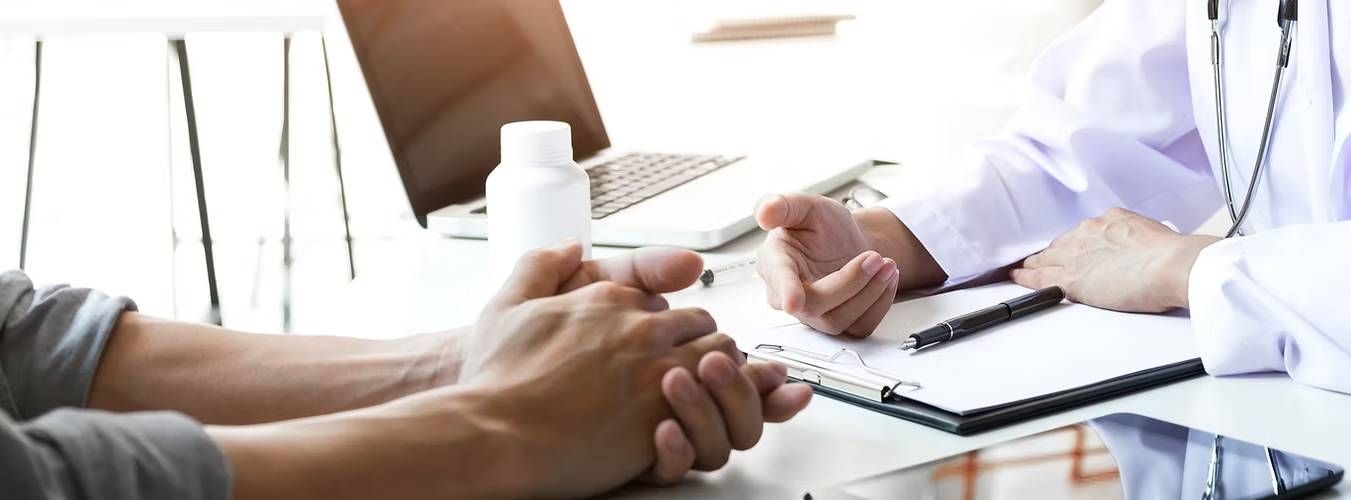 A doctor and patient sit across a desk in discussion

