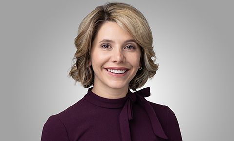 Smiling person in a burgundy top against a gray background