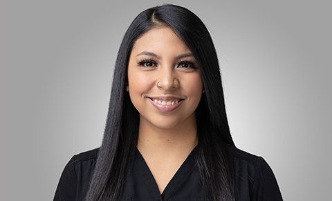 Smiling woman with long black hair against a gray background