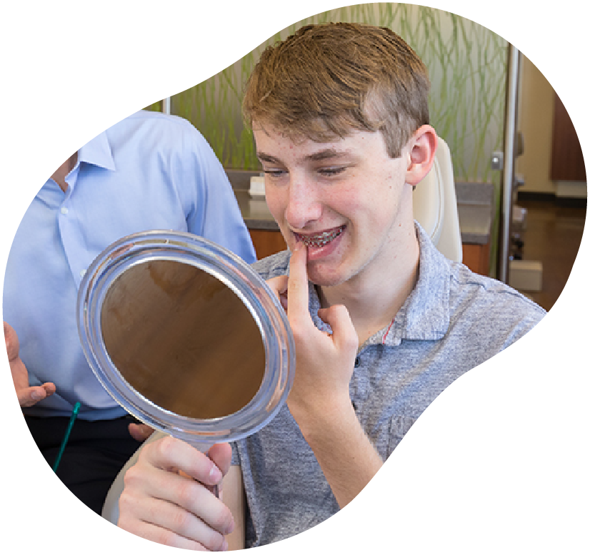 Person applying lip gloss while looking into a handheld mirror