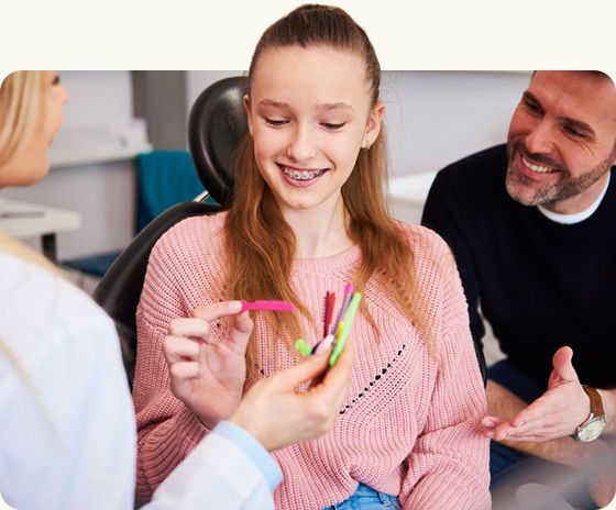 Dentist showing colorful dental picks to a smiling child during a checkup