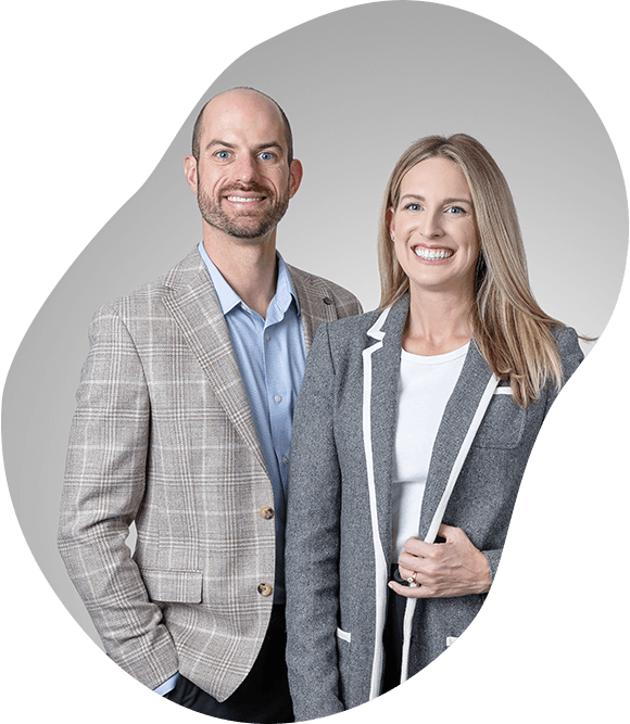 Two smiling professionals in gray blazers posed against a light gray background