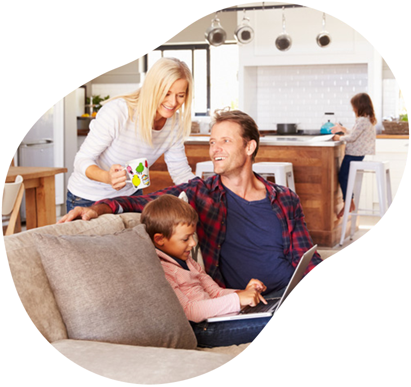 Family relaxing on a couch while a woman serves coffee in a bright kitchen living room