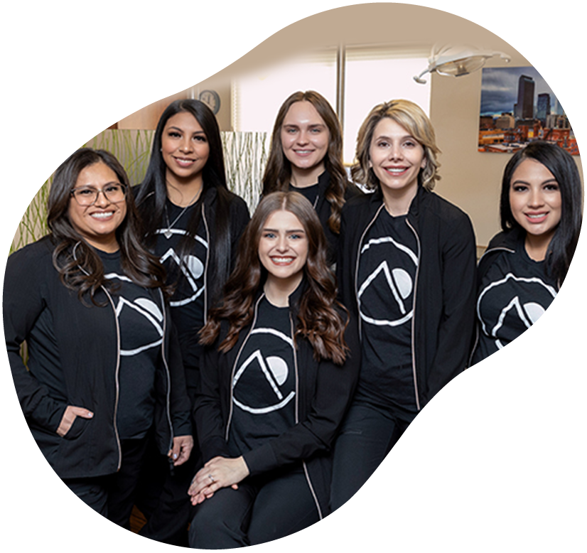 Five people in black jackets and shirts with white logos posing indoors, smiling.