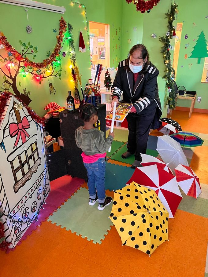 Un homme masqué se tient à côté d'une petite fille dans une pièce décorée pour Noël.