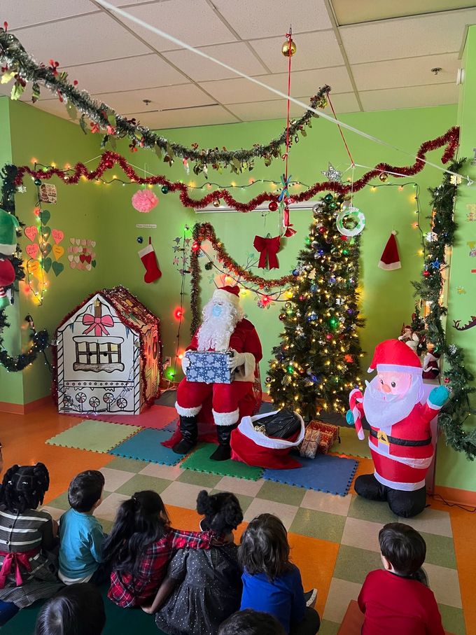 Un groupe d'enfants sont assis devant un arbre de Noël et regardent le Père Noël.