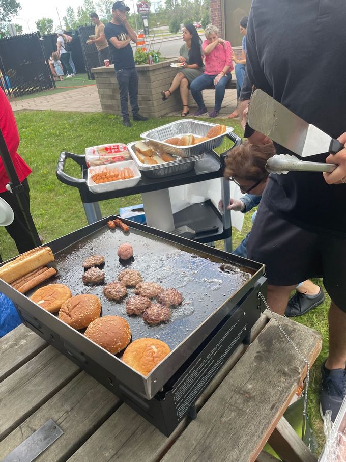 Un groupe de personnes cuisinent de la nourriture sur un gril à l'extérieur.