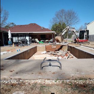 Pool demolition in progress; excavator, exposed concrete and debris.
