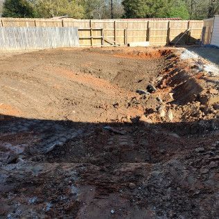 Excavated backyard; brown dirt, fence in background. Sunny day.