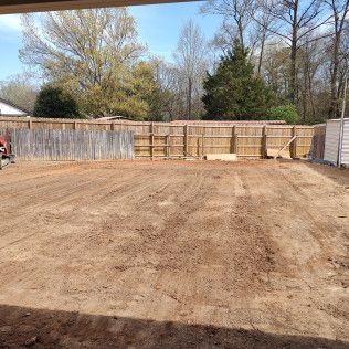 Brown dirt yard, wood fences in background, trees and shed on right, open sky.