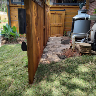 Wooden fence with a path leading to a shed with a small wooden door.