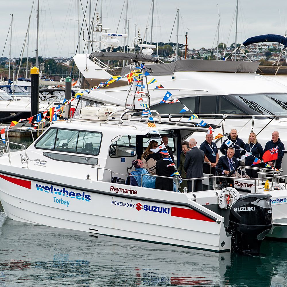 Princess Anne on boat with people on deck in a harbor, decorated with flags, and branded