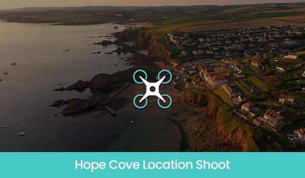 Aerial view of Hope Cove, Devon, with a drone logo, showcasing the coast and buildings.