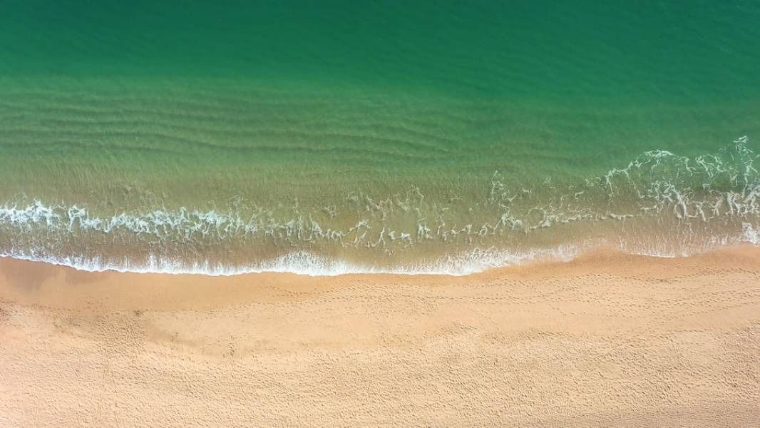 Sandy beach with foamy waves and turquoise water.