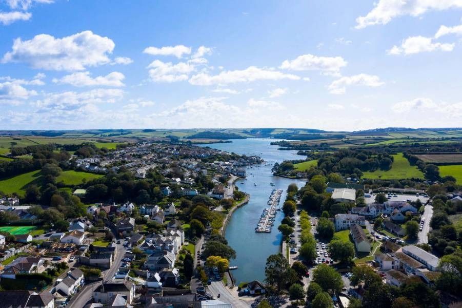 Aerial view of a coastal town and harbor with boats on a sunny day.