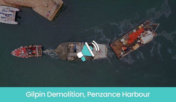 Aerial view of a boat demolition in Penzance Harbour, two vessels near each other with the damaged boat in the center.