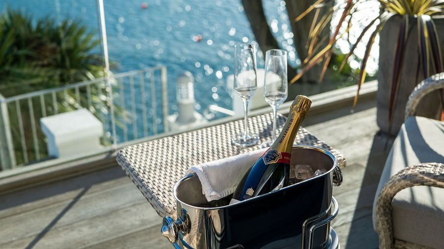 Champagne bottle in ice bucket on a table with water view and glasses.