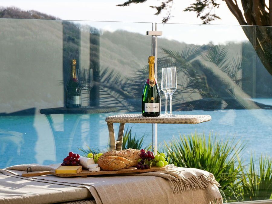 Table set with champagne, glasses, and charcuterie board by a scenic ocean view.