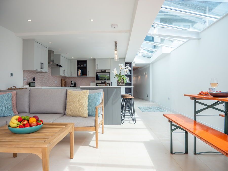 Modern kitchen and living area with a skylight, a gray couch, and an orange picnic table.