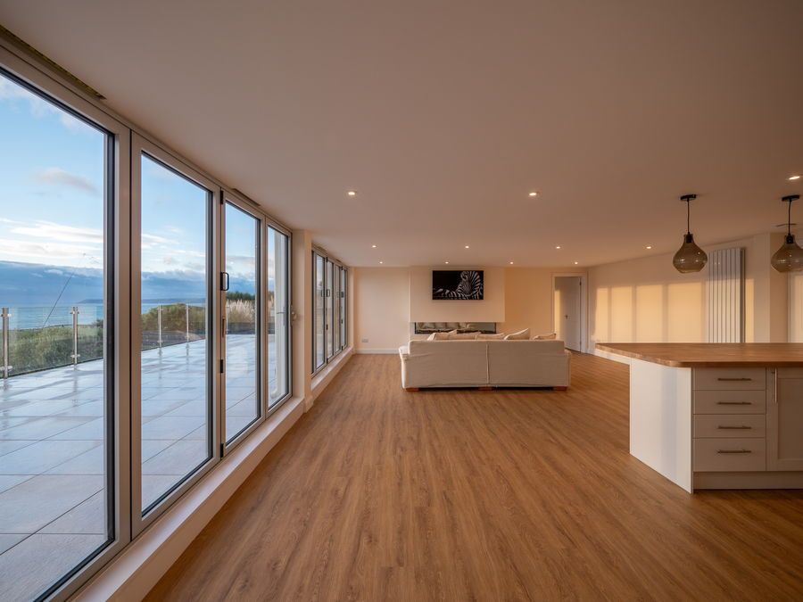 Spacious living area with large windows, wood flooring, and a view of the outdoors.