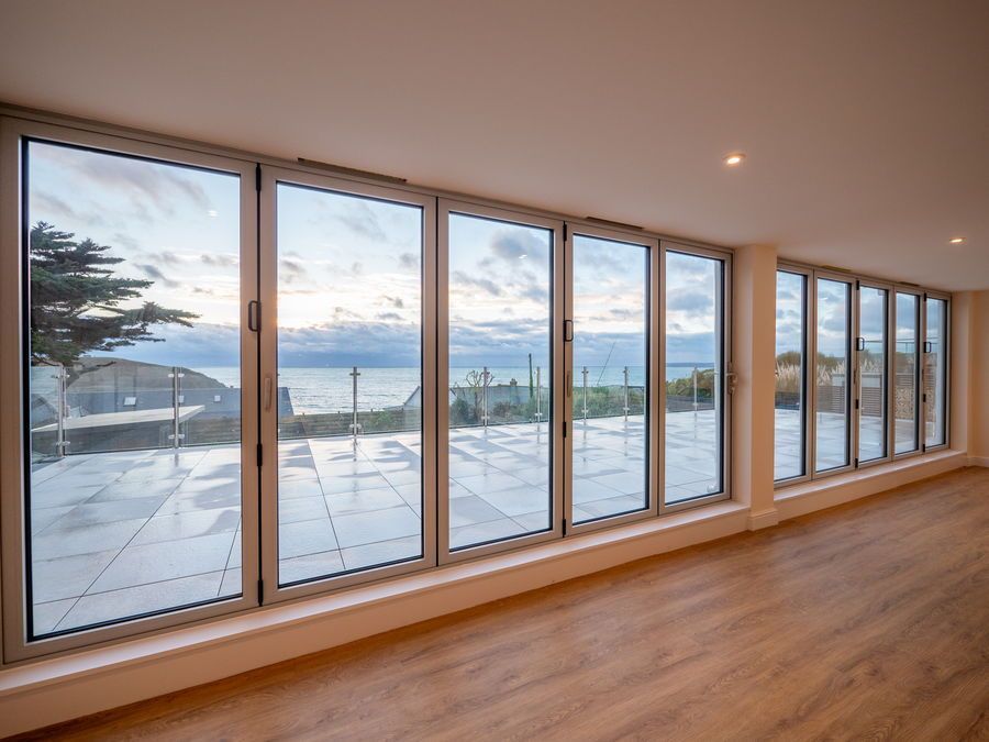 Large folding glass doors overlook a coastal view.