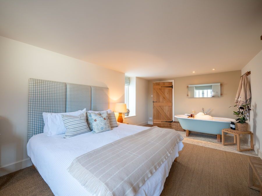 Bedroom with a light blue tub, large bed, and wooden accents.