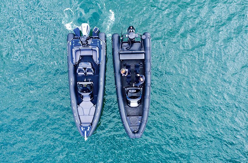 Two dark-colored rigid inflatable boats (RIBs) on turquoise water, viewed from above.