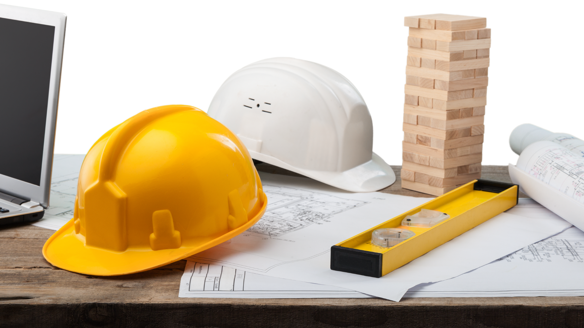 A wooden table with hard hats , a laptop , a level , and a stack of jenga blocks.