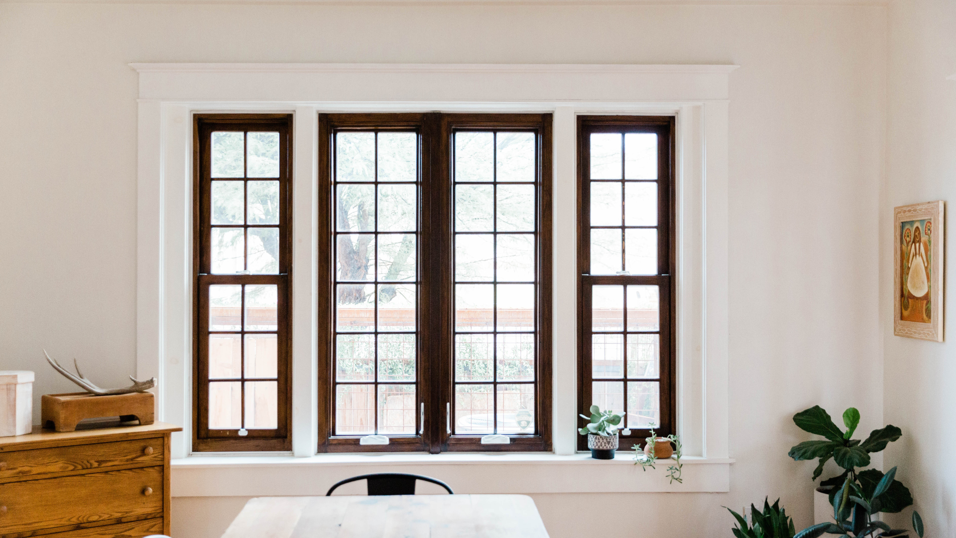 A dining room with a table and chairs in front of a large window.