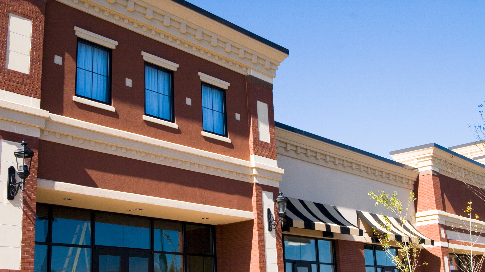 A brick building with blue windows and a black and white awning