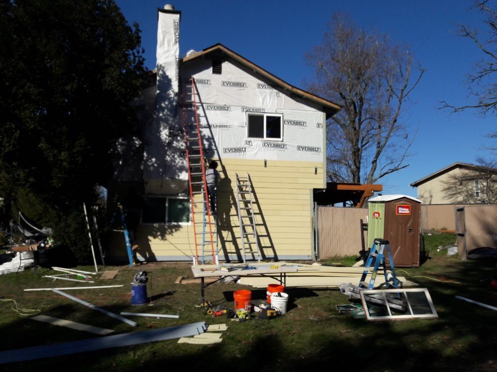 A house is being remodeled with a ladder in the backyard